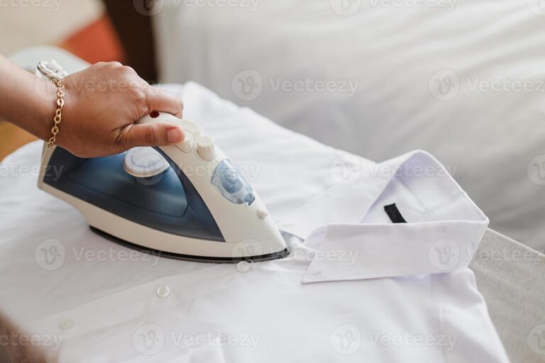 manos planchando una camisa blanca