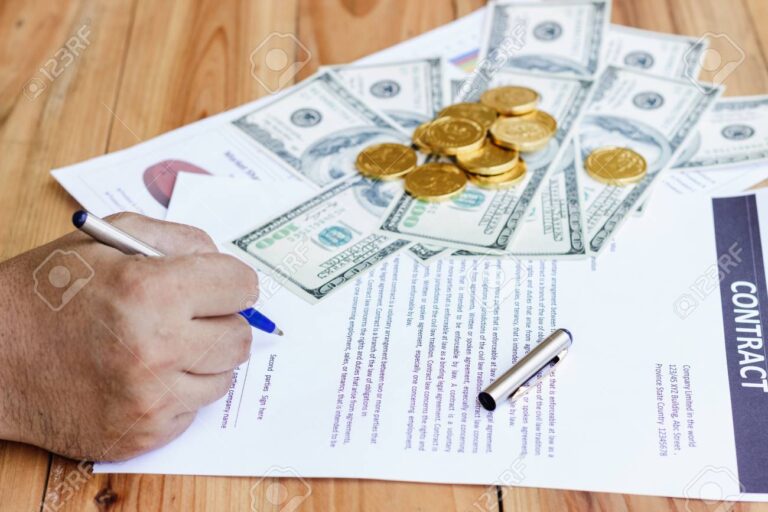 manos sosteniendo monedas sobre un contrato